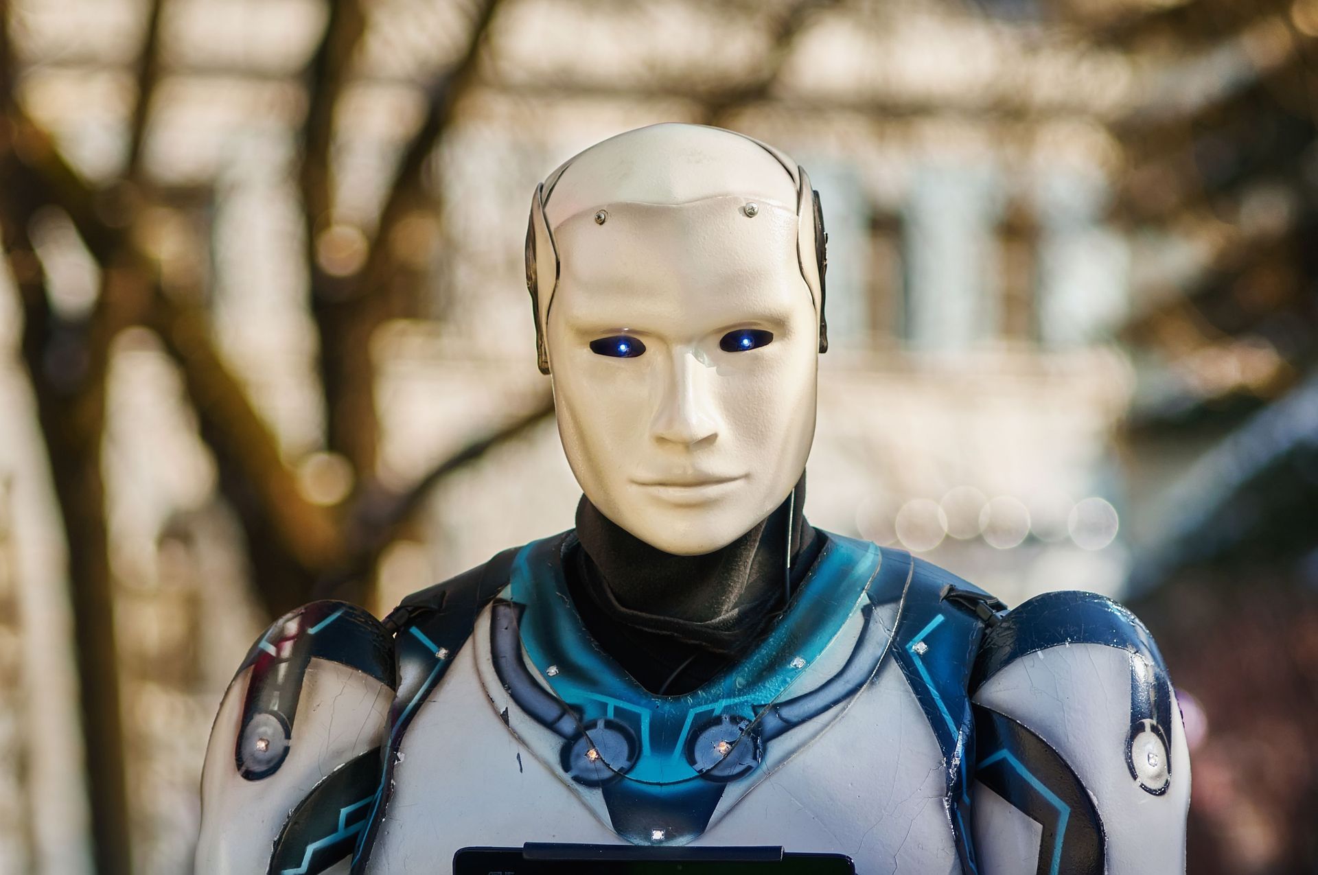 Humanoid robot AI with blue accents and glowing eyes against a blurred outdoor background