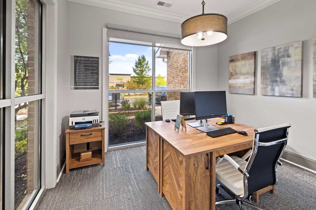 Leasing office workstation with computer and printer near a large window.