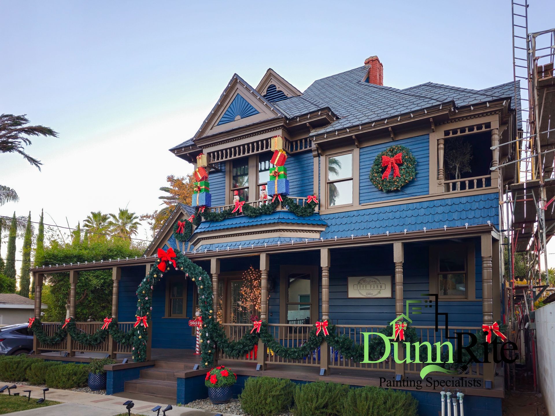 Blue Victorian house decorated for Christmas with garlands and wreaths.