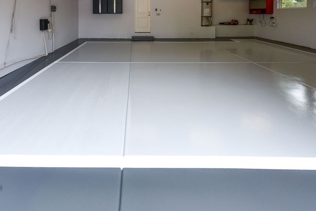 Newly coated garage floor, light gray with gray border and white lines.