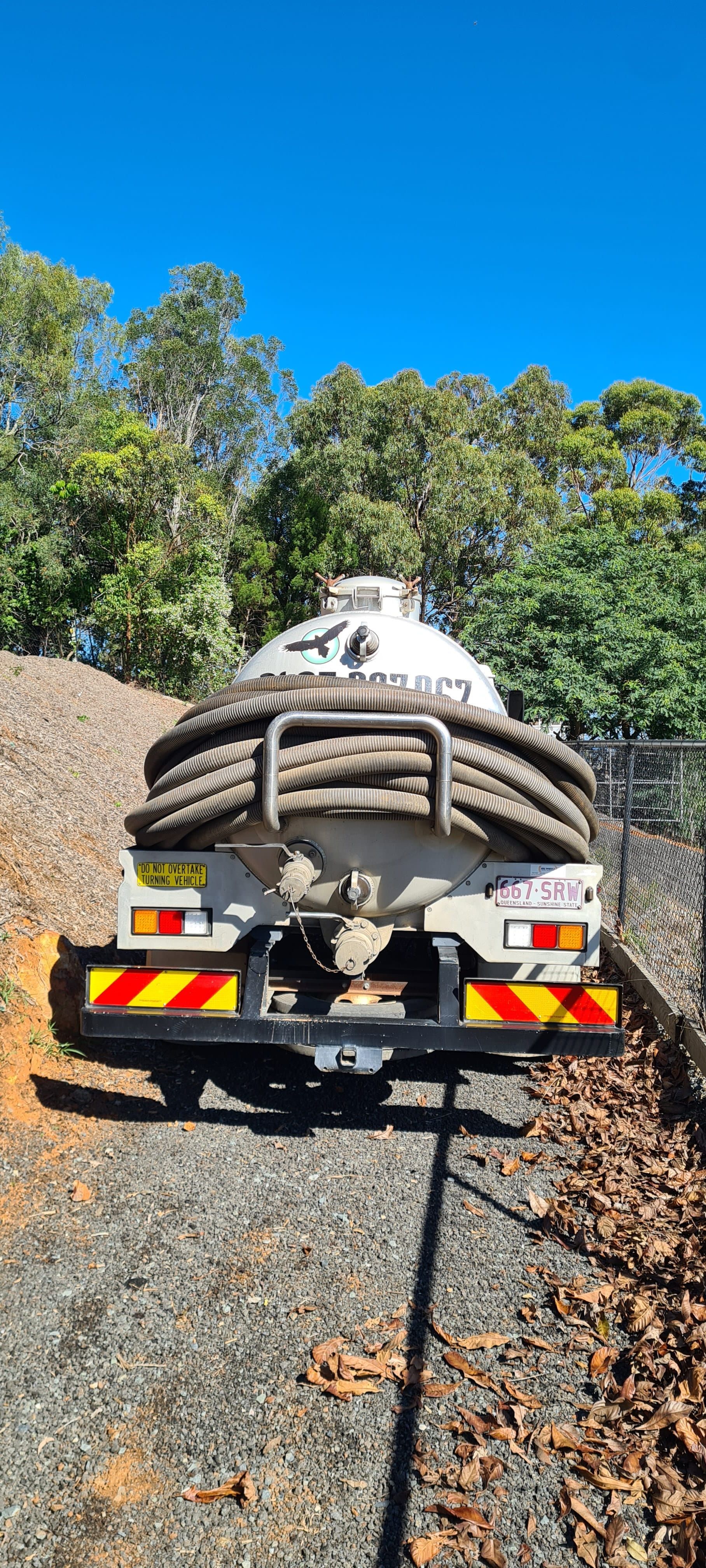 A tanker truck on a gravel road, backed by trees and a bright blue sky — Raptor Waste Management in Coolangatta, QLD