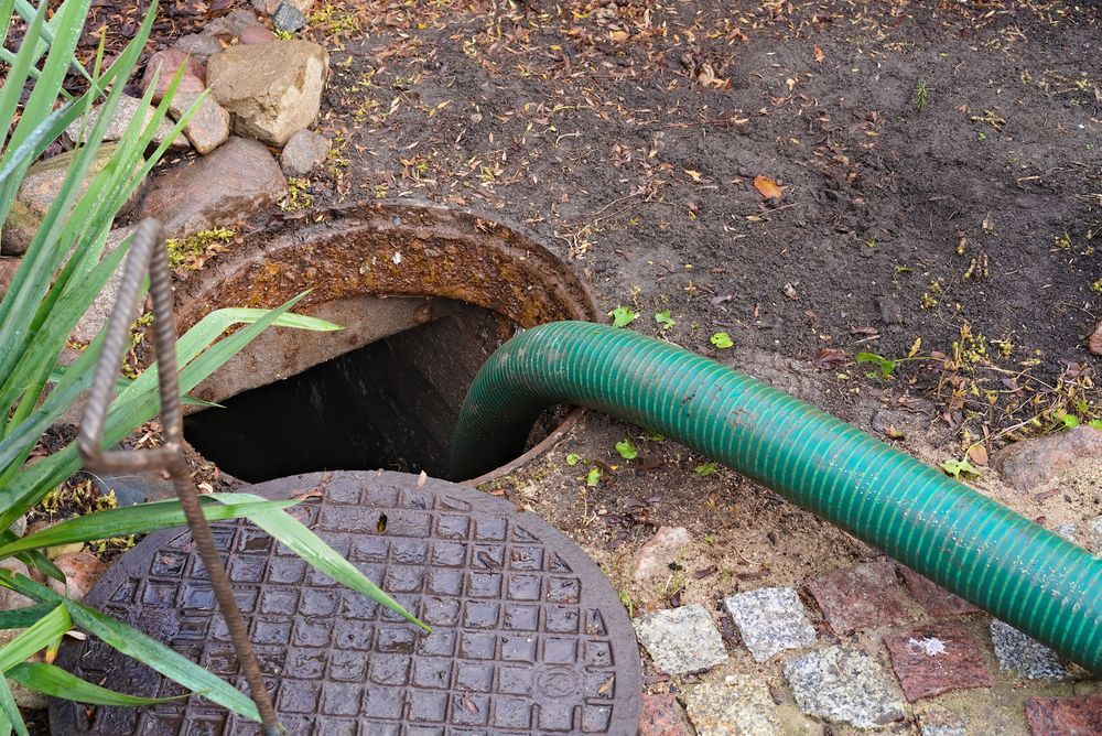 Green Hose Inserted Into an Open Sewer Access Point — Raptor Waste Management In Coomera, QLD