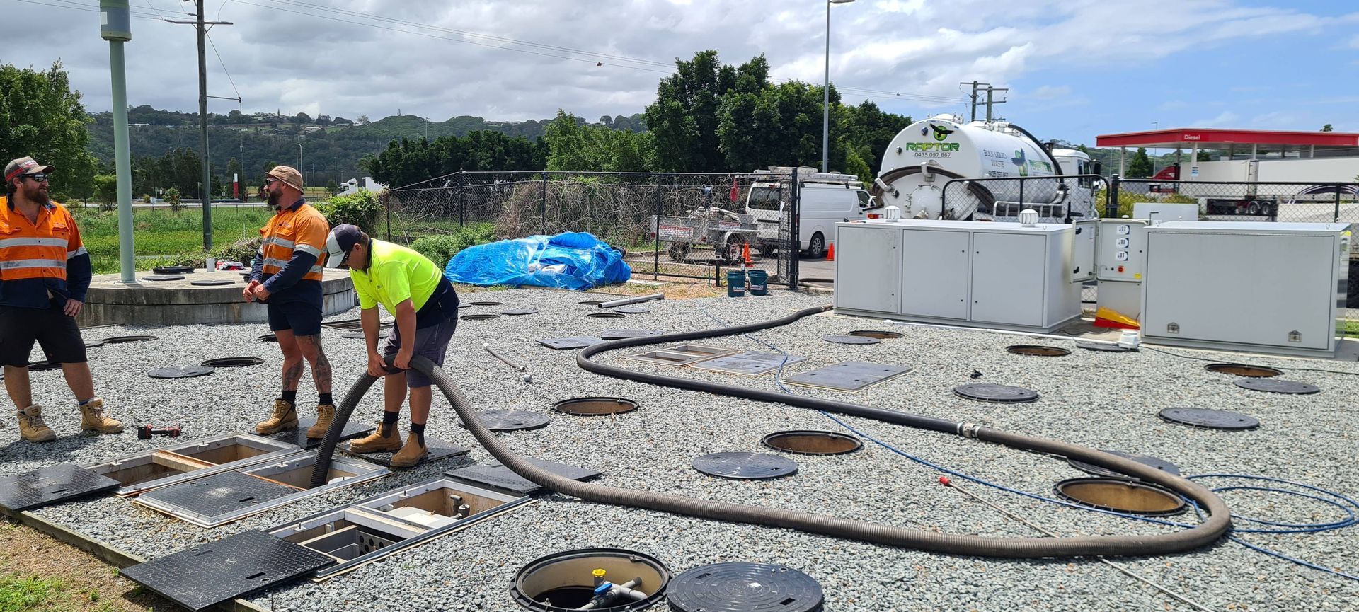 Three workers pumping a tank at a worksite. The workers are wearing safety vests and boots. Gravel surrounds open access points. — Raptor Waste Management in Coolangatta, QLD