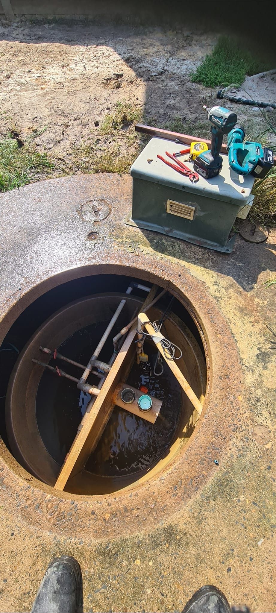 Open manhole with tools and a device inside, set in a stone surface — Raptor Waste Management in Coolangatta, QLD