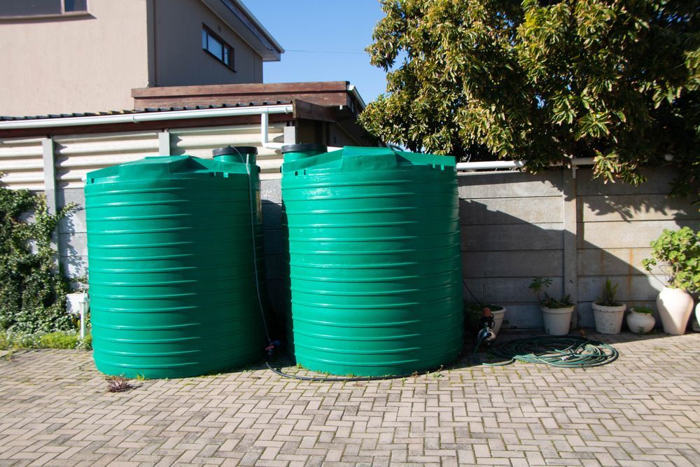 Two Green Water Storage Tanks on a Paved Area — Raptor Waste Management In Tweed Heads, NSW