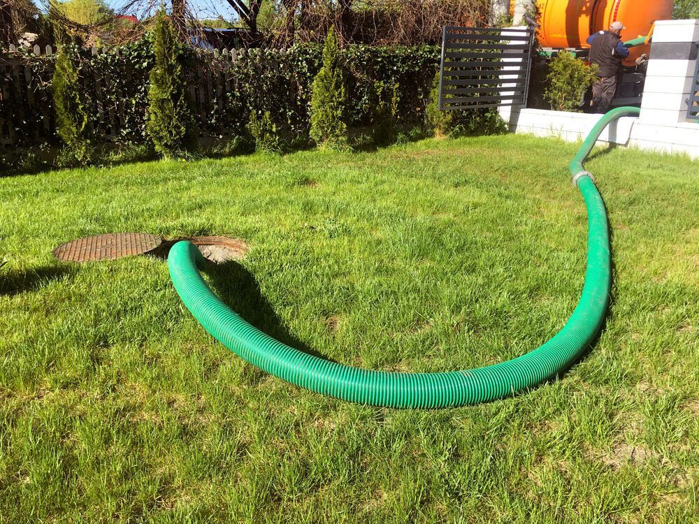 Green Hose on Grass Connected to a Drain Cover — Raptor Waste Management In Uki, NSW