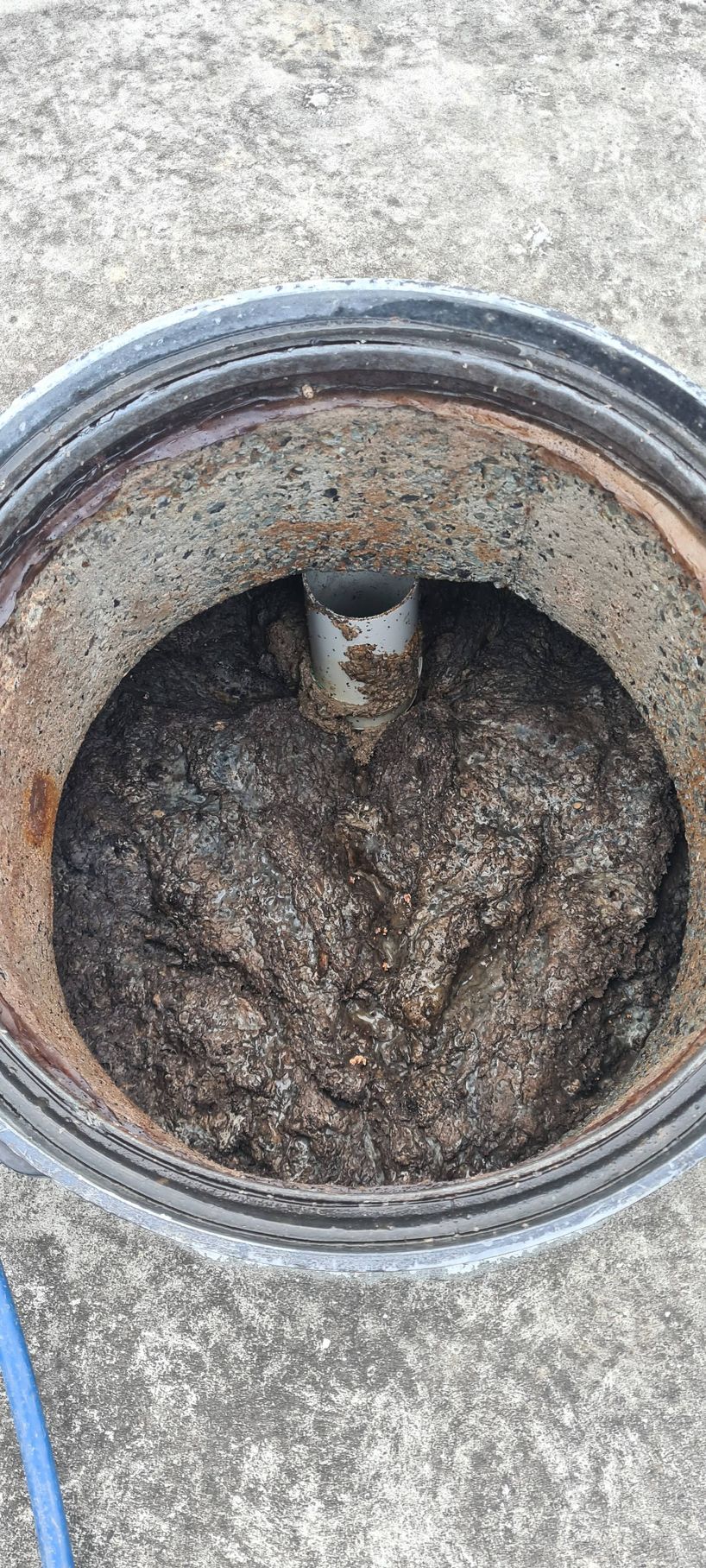 An open, circular container filled with dark, granular material; a pipe rises from the center — Raptor Waste Management in Coolangatta, QLD
