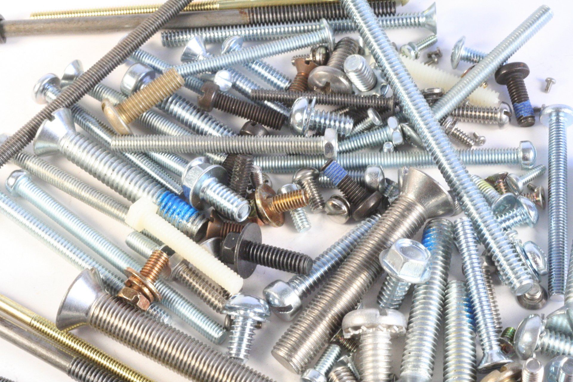 A pile of screws and bolts on a white surface