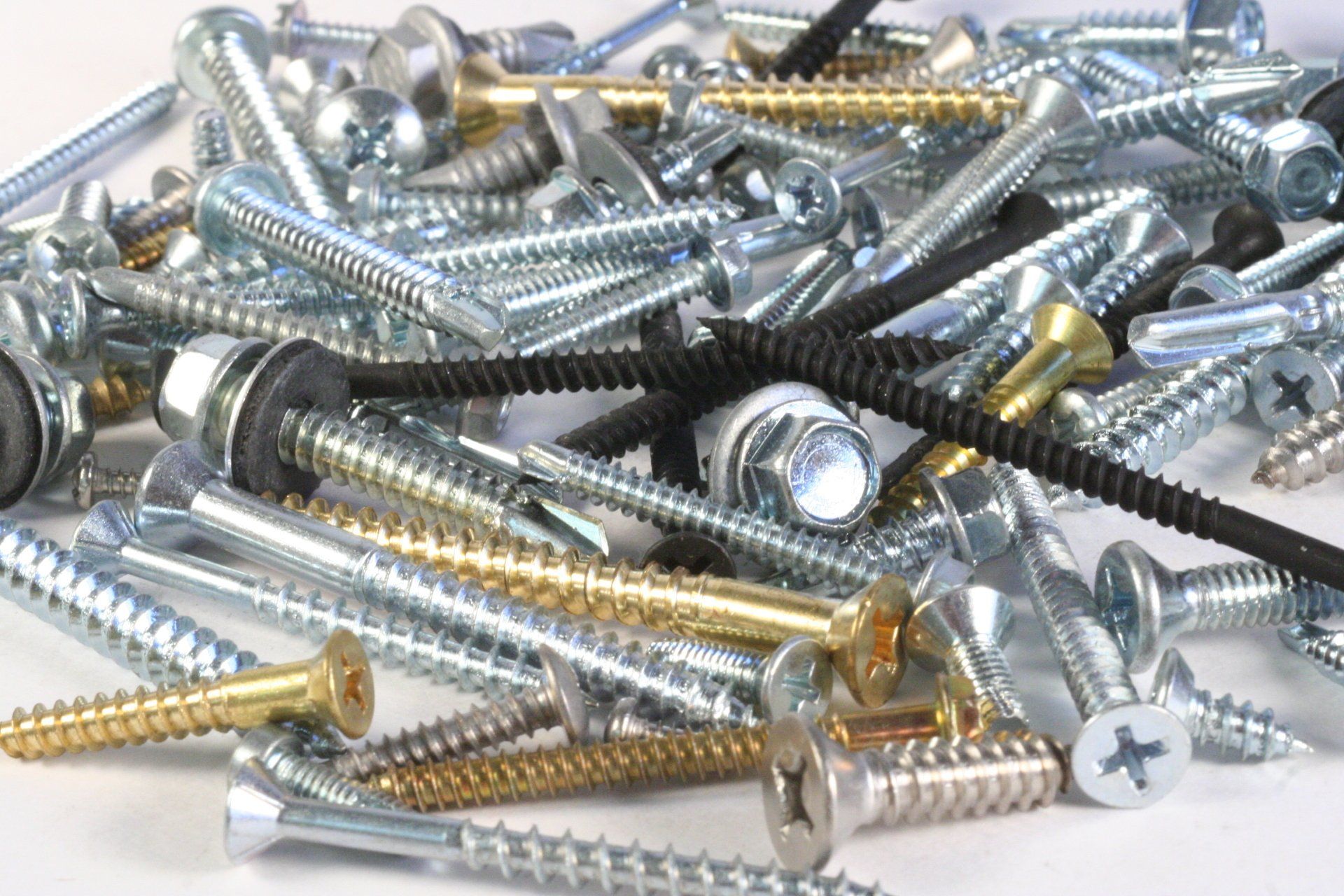 A pile of different types of screws on a white surface