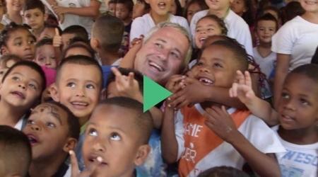 A man is standing in front of a crowd of children.