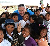 A man is posing for a picture with a group of children. ANDY STEIN