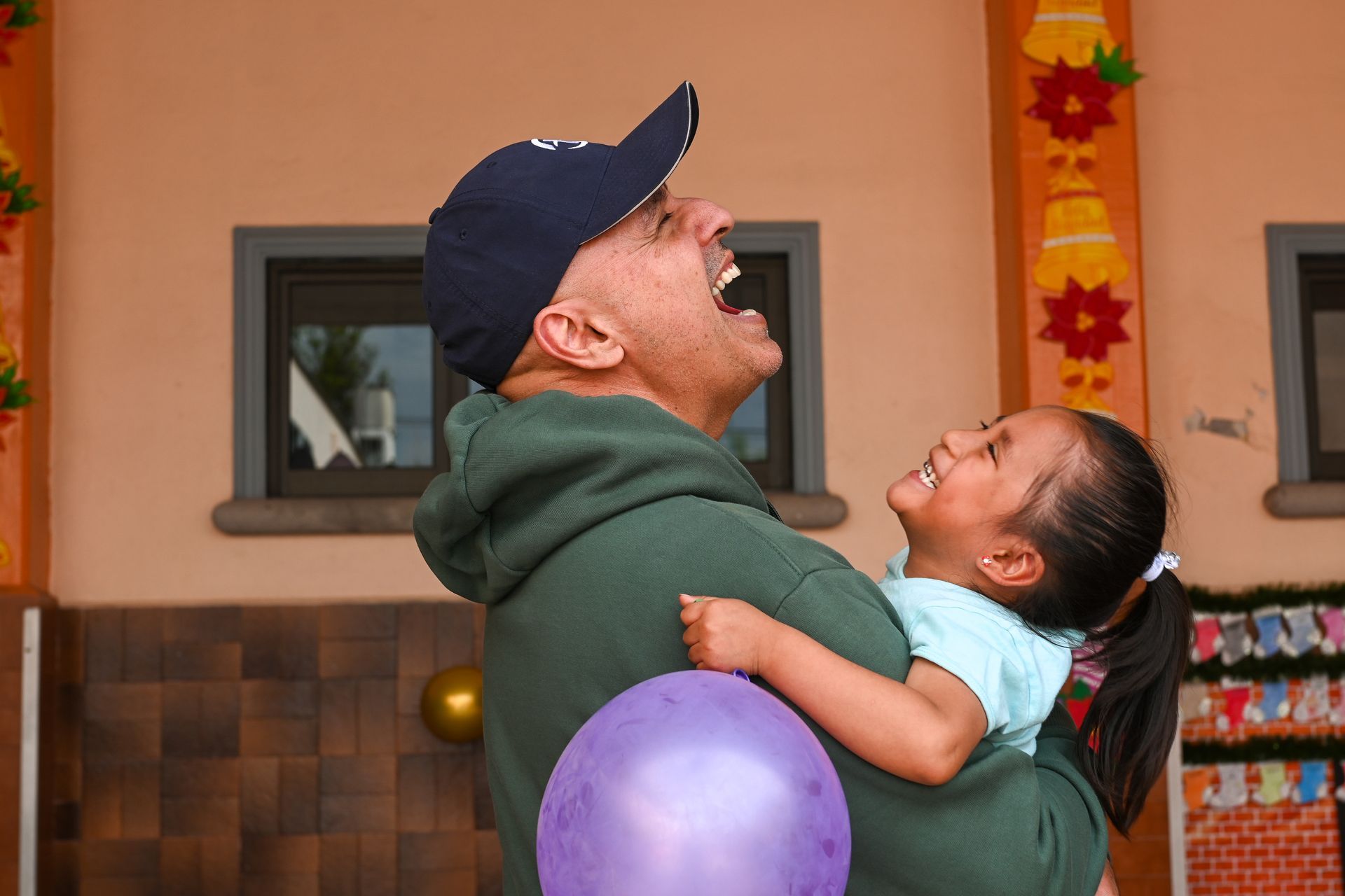 A man is holding a little girl in his arms and laughing.