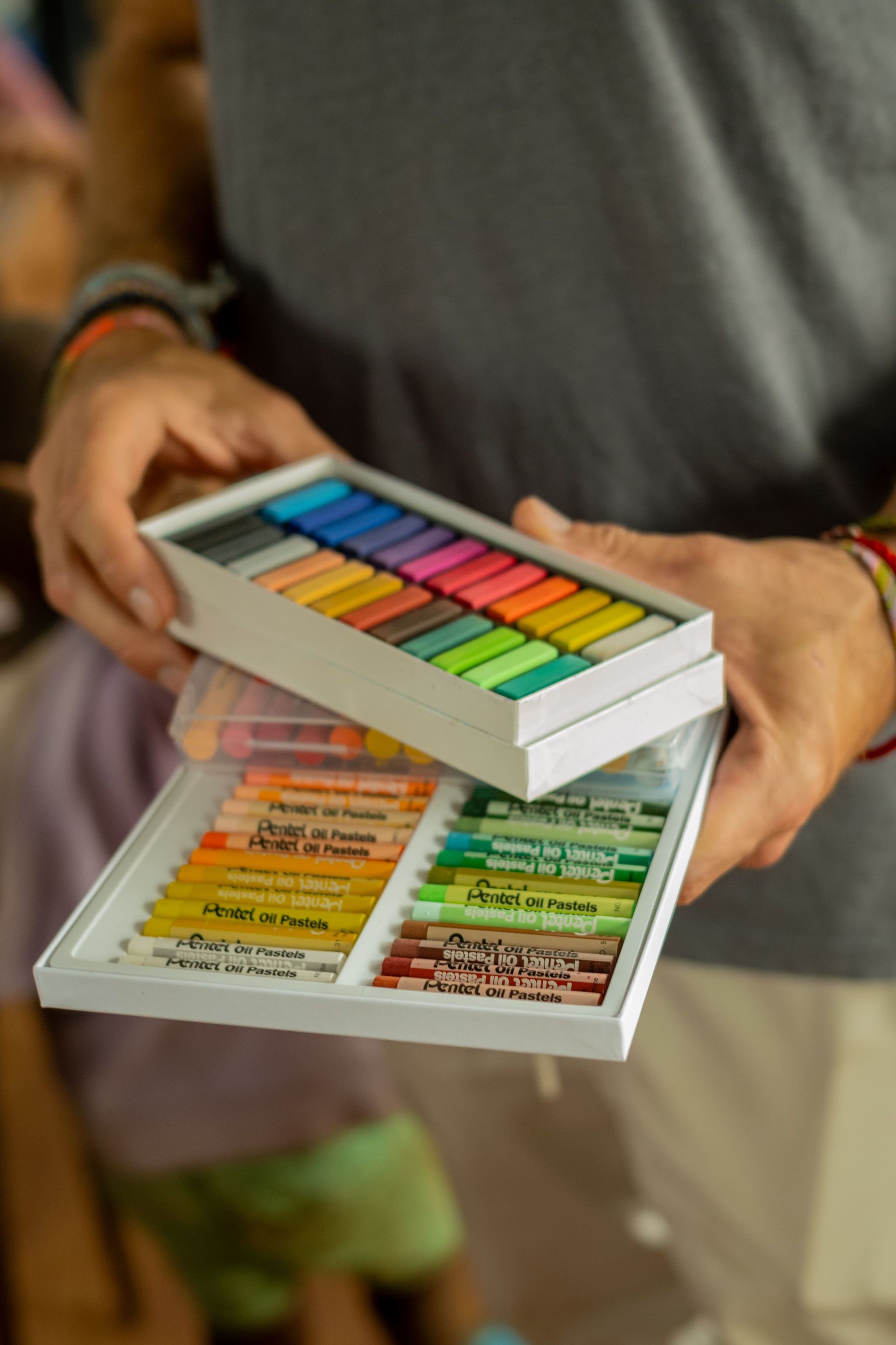 A man is holding a box of crayons in his hands.