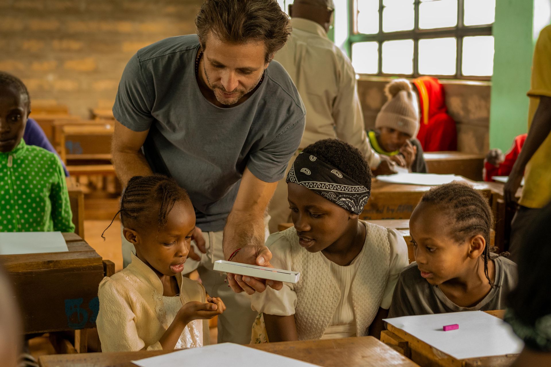 A man is teaching a group of children in a classroom.