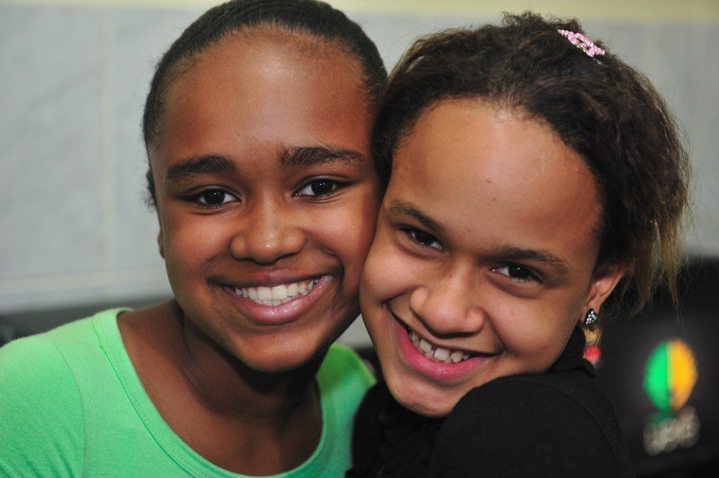 Two girls are posing for a picture and smiling for the camera