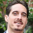 A man with a beard and mustache is smiling for the camera. ERIC RICAURTE