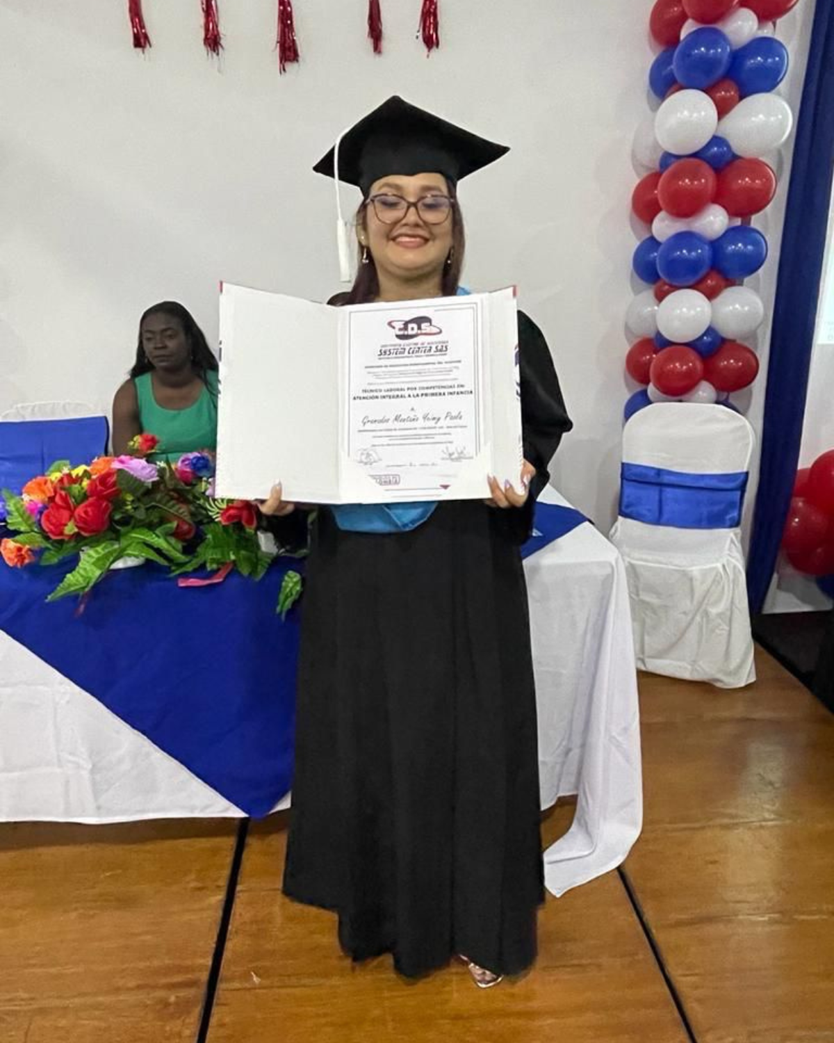 Yeimmy Paola Grenados in a graduation cap and gown is holding a diploma. osf fundamor colombia andy stein