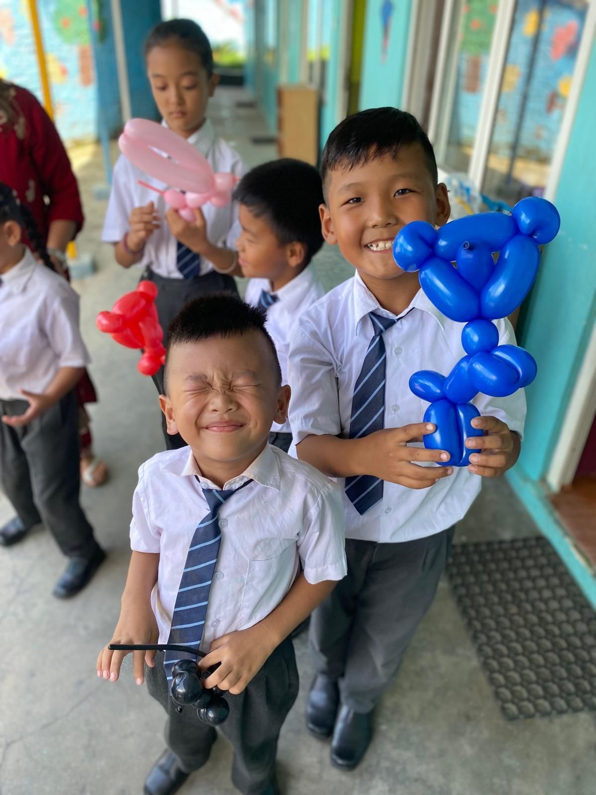 A group of Nepalese children in school uniforms and ties are holding balloons. Andy Stein of orphaned starfish