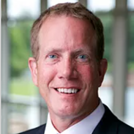 A man in a suit and tie is smiling for the camera. JOHN PELANT