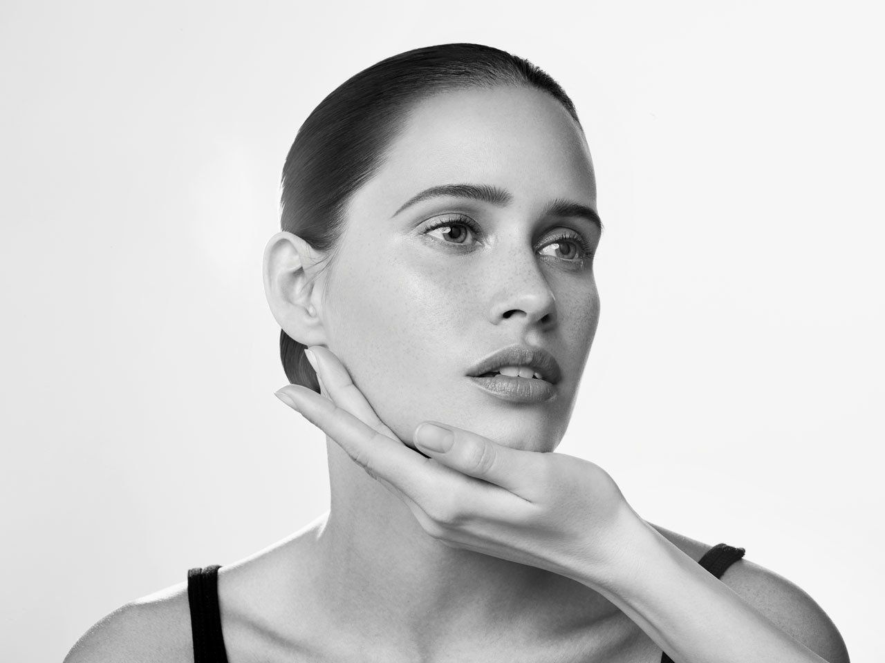 A woman is touching her face with her hand in a black and white photo.