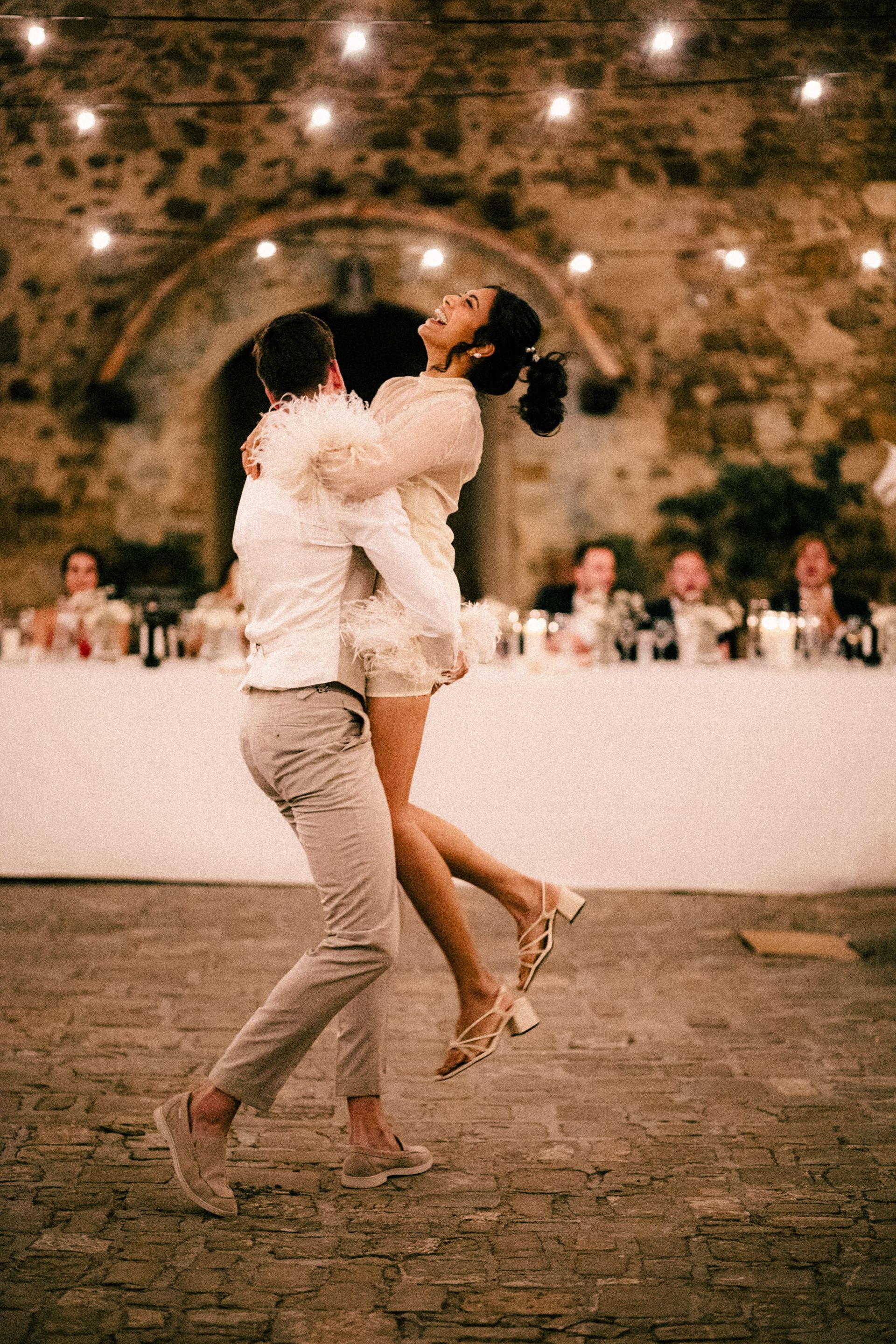 Een man houdt een vrouw in zijn armen terwijl hij danst op een huwelijksreceptie.