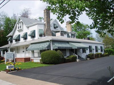 White building with green-striped awnings and a dark driveway, funeral home.