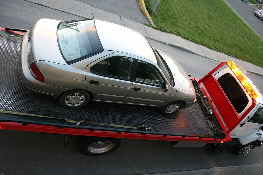 Silver car loaded onto a red and white tow truck.