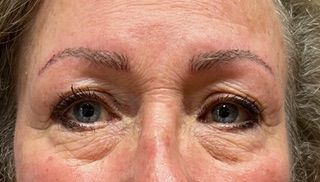 A close up of a woman 's face with blue eyes and red cheeks.