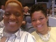 two women are smiling for a picture while sitting next to each other in a room .