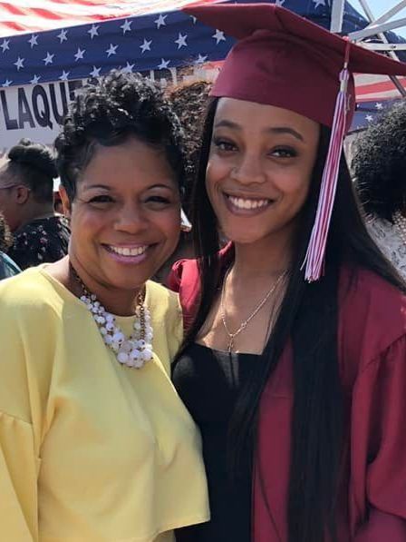 two women posing for a picture with one wearing a graduation cap and gown