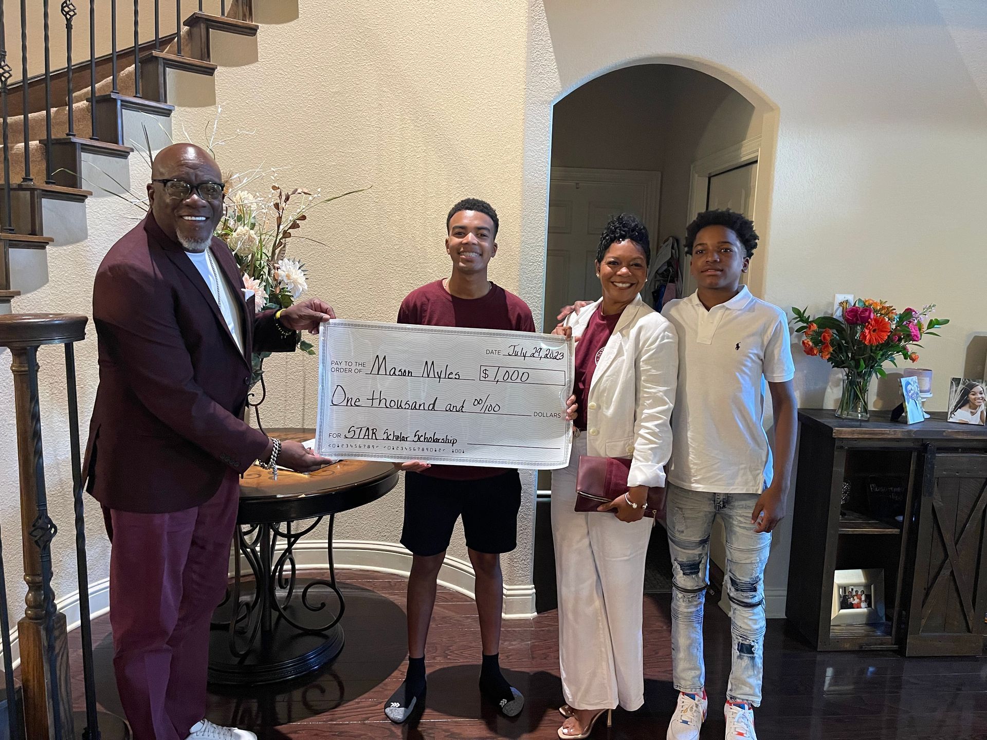 A man is giving a check to a family in a living room.