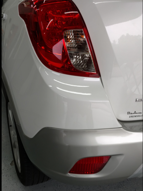 A person is using a tool to fix a dent on a car. A person is using a tool to fix a dent on a car.