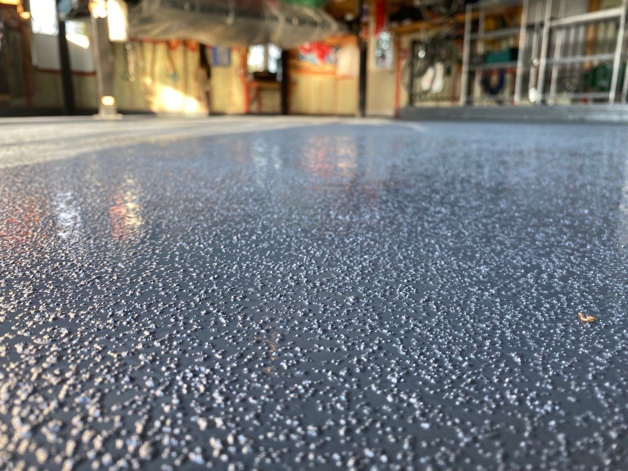 a close up picture of epoxy flooring job that crystal clear has completed. a grey epoxy that is antislip that easily allowes for cars to drive on it in any condition.  h