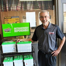 Man standing beside stacked Interstate Batteries.