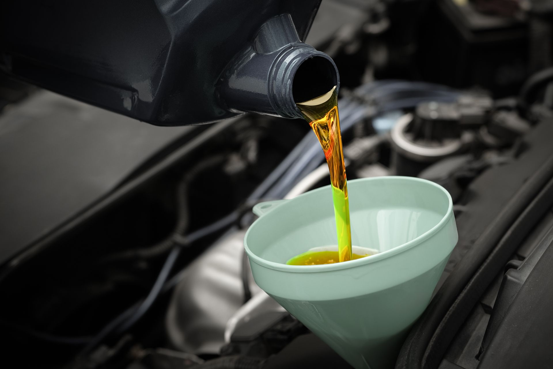 Oil being poured from a car into a funnel for an engine oil change