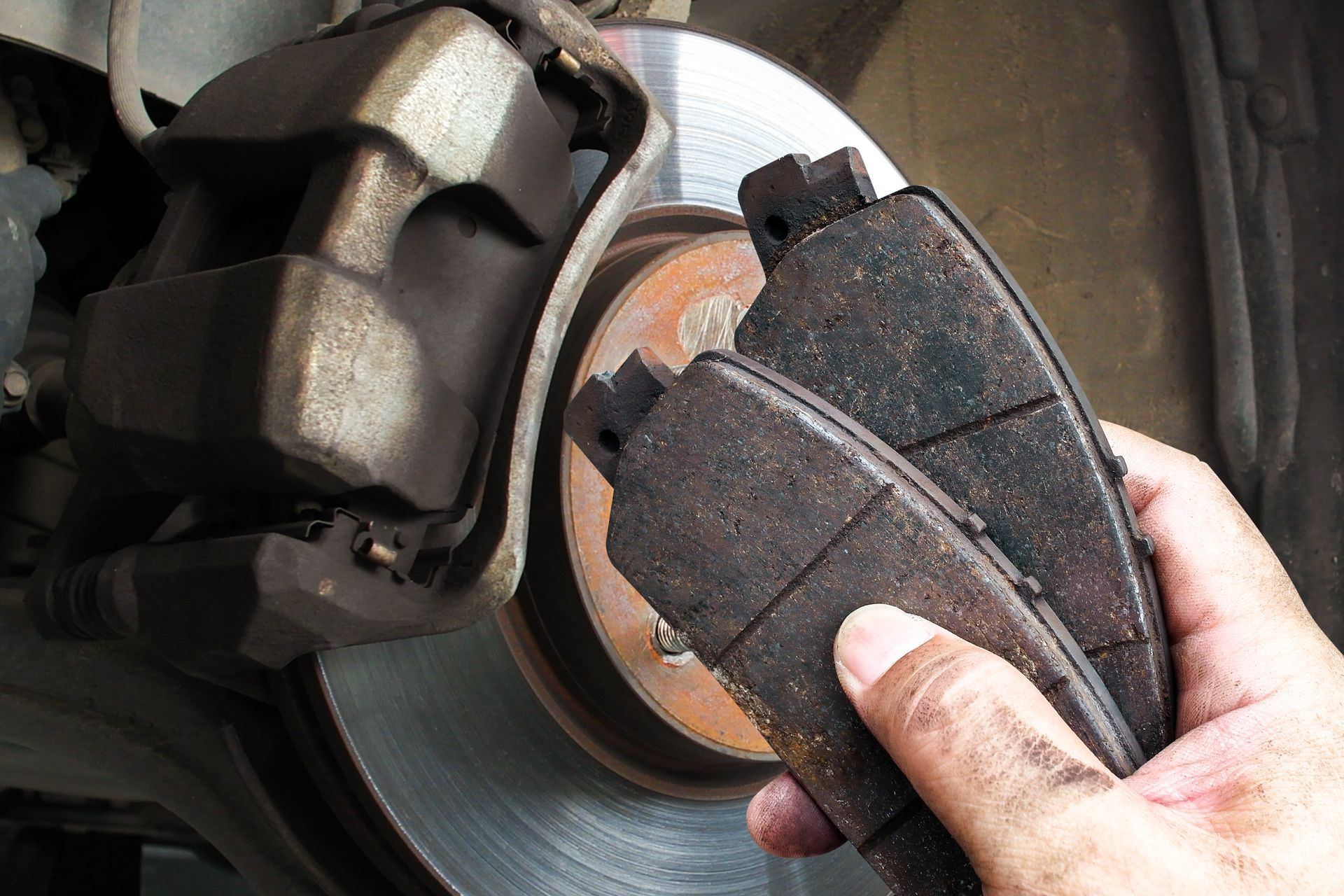 Close-up of a hand replacing a car brake pad on a wheel rotor