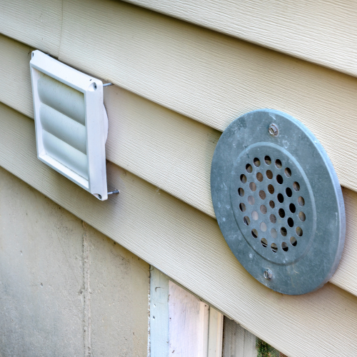 Two exterior vents on beige siding: a rectangular louvered vent and a circular screened vent.