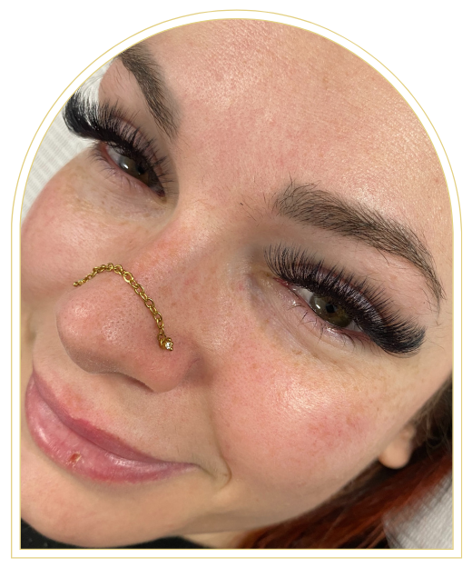 A close up of a woman 's face with long eyelashes and a nose ring.