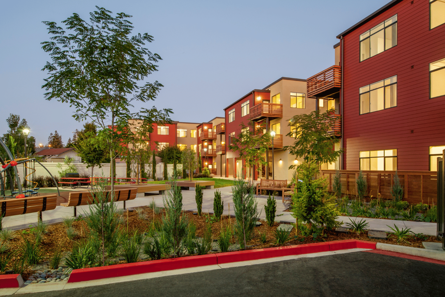 Modern brick apartment buildings at dusk with landscaped gardens and walkways