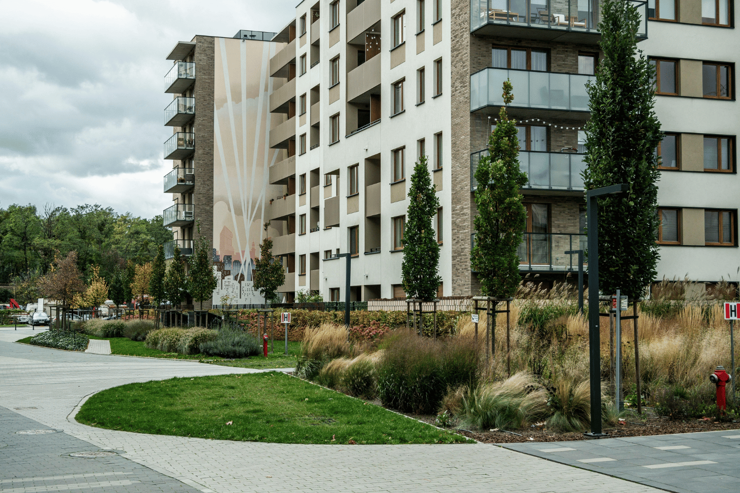 Modern apartment buildings beside a landscaped courtyard with pathways and trees