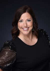 A woman in a black dress is smiling for the camera.