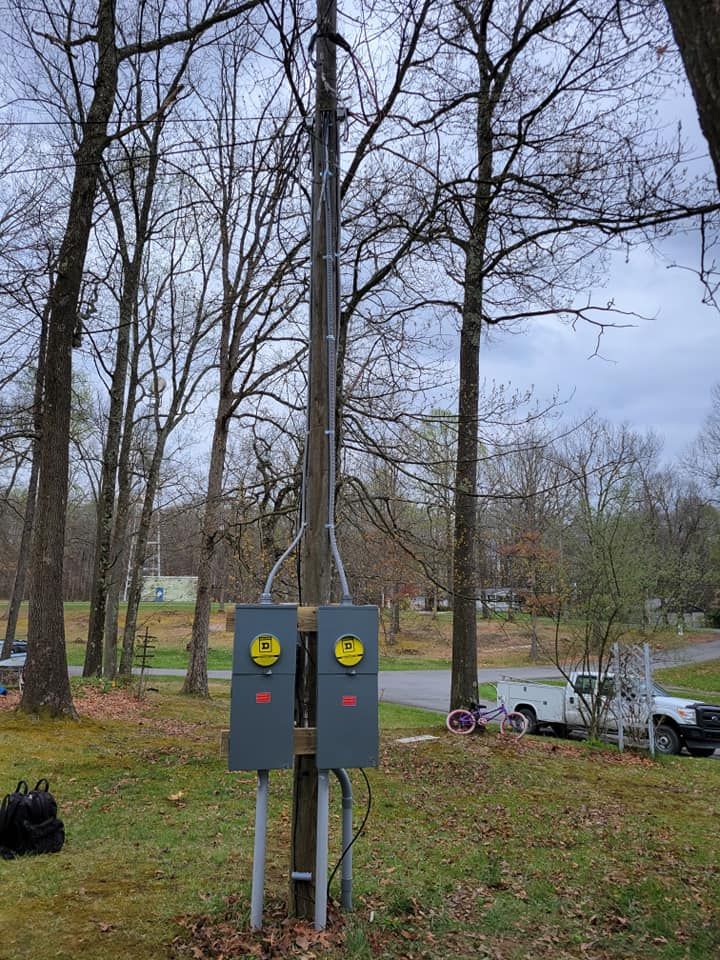 A couple of electrical boxes sitting on top of a pole in the middle of a field.