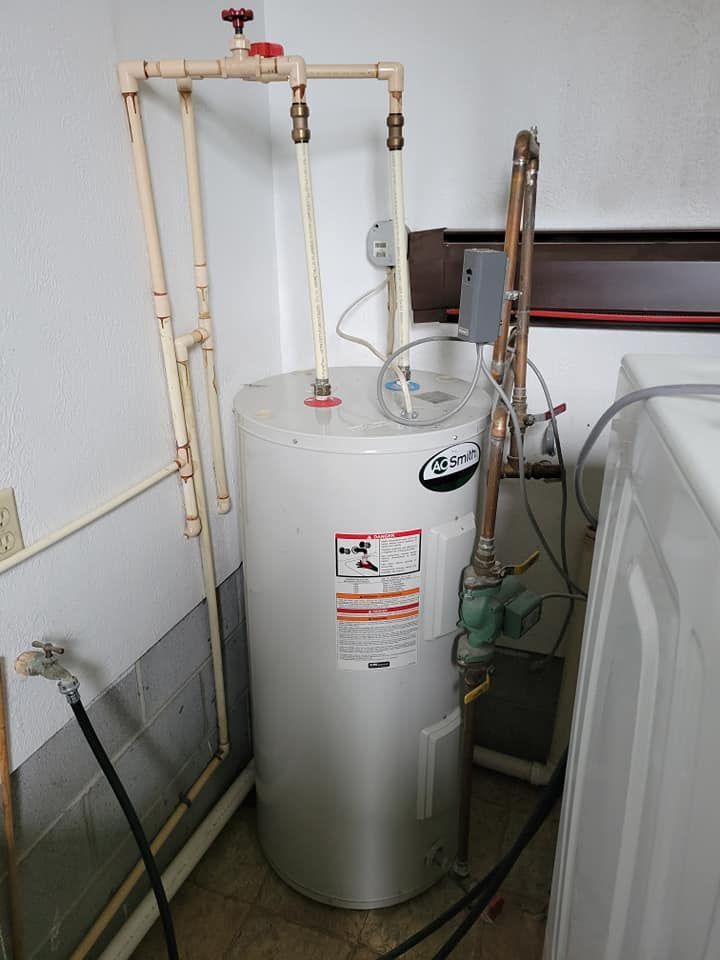 A white water heater is sitting in a laundry room next to a washer and dryer.