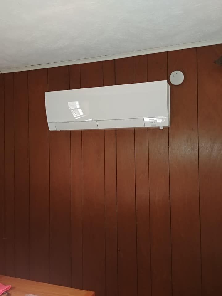 A white air conditioner is hanging on a wooden wall.