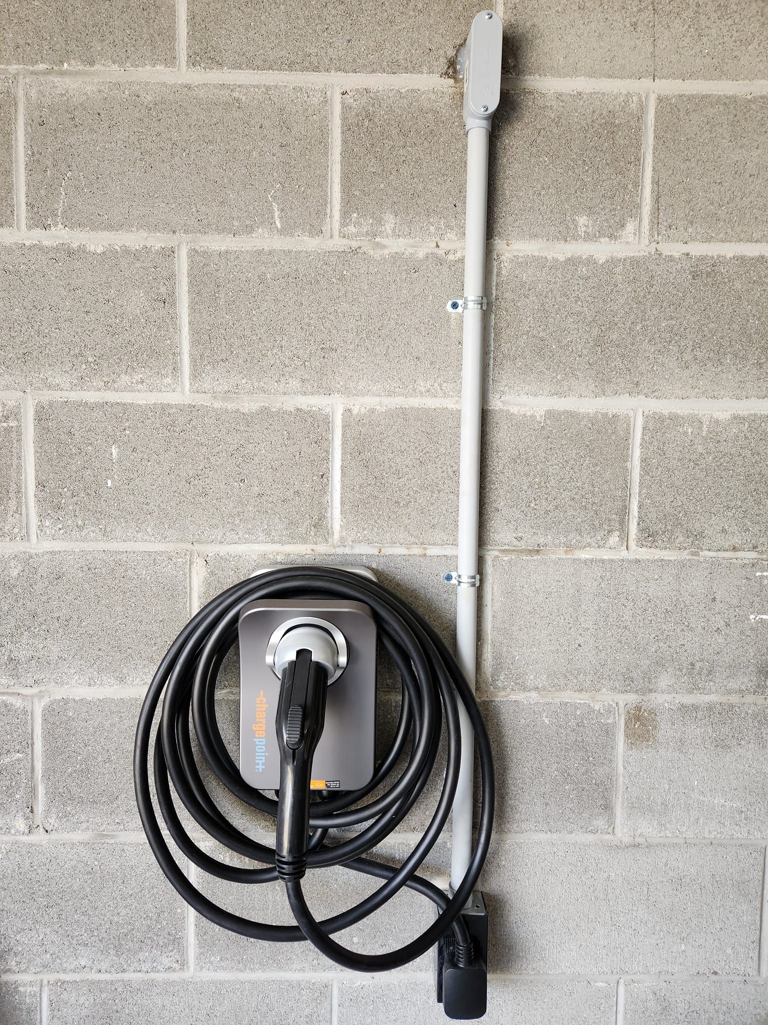 A electric car charger is attached to a brick wall.