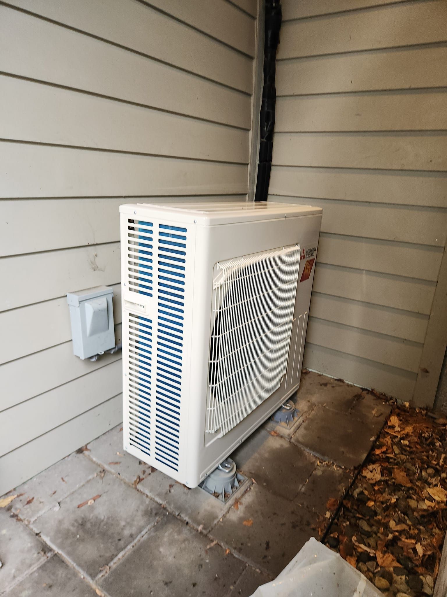 A white air conditioner is sitting on the side of a house.