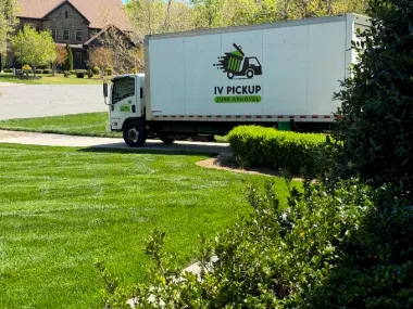 White pickup truck with IV PICKUP logo parked on a green lawn in a residential neighborhood