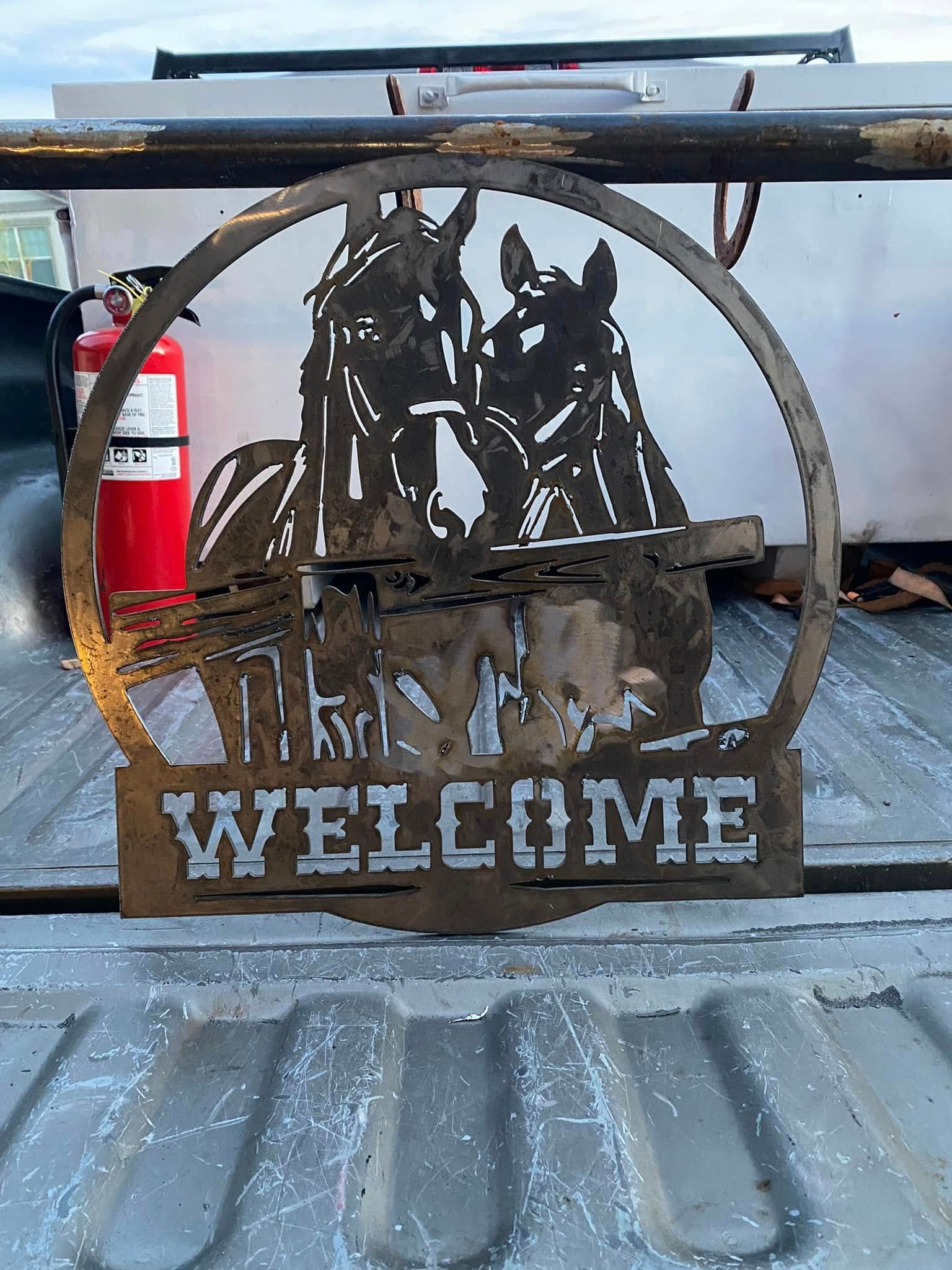 Rustic metal “WELCOME” sign with elk silhouette in a truck bed, with a red fire extinguisher nearby