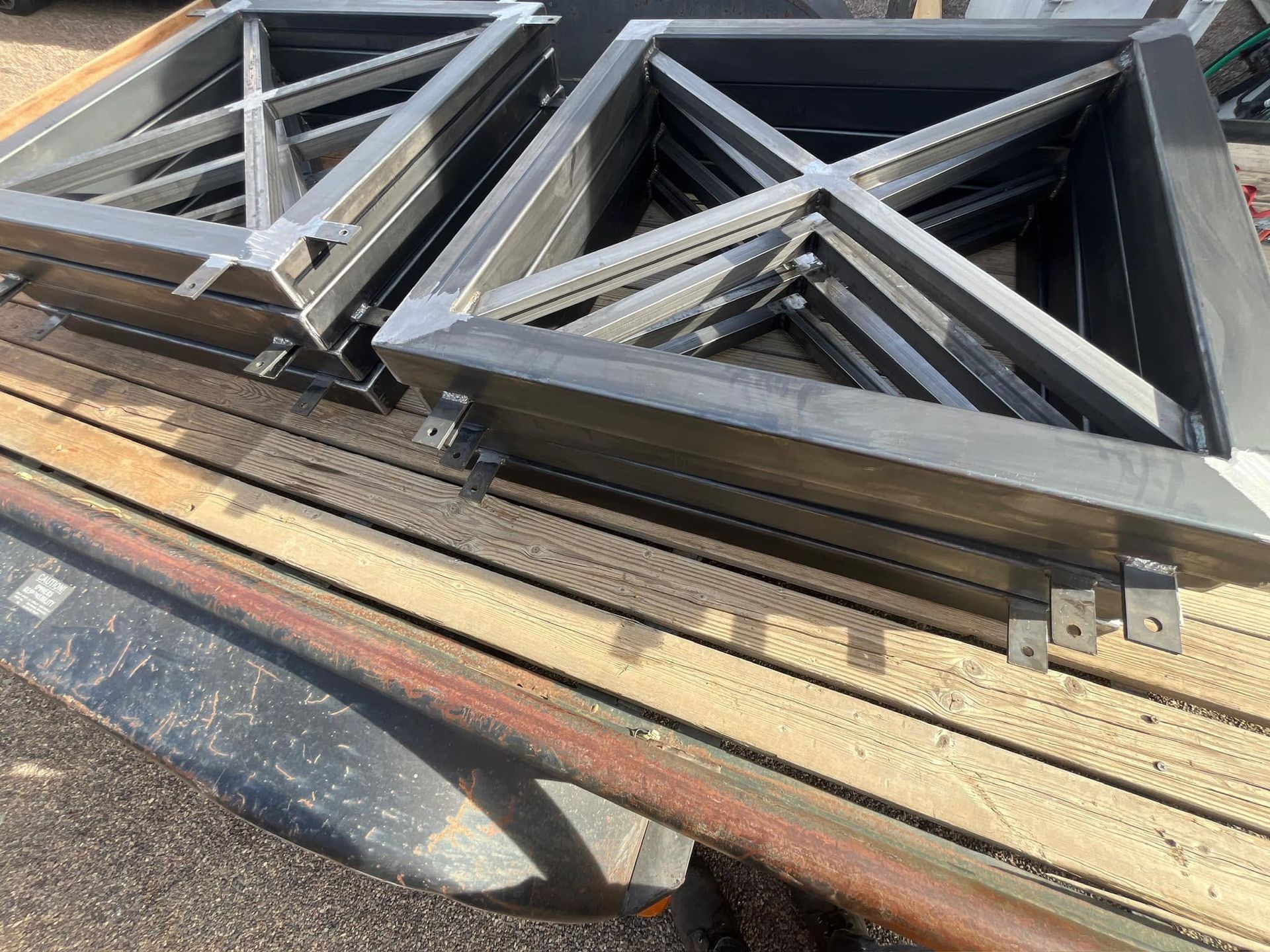 Stacked black metal truss frames on a flatbed trailer in a work yard