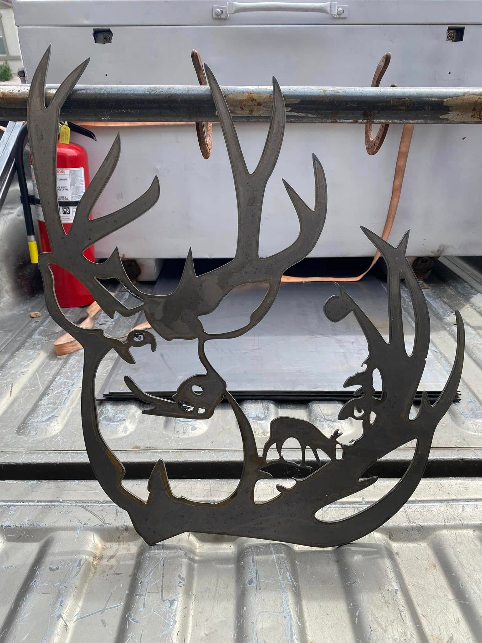 Black metal deer-antler decoration leaning against a truck tailgate, with a red fire extinguisher in the background